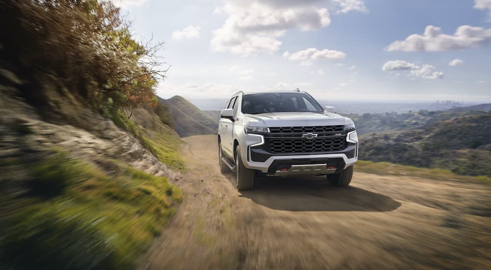 A white 2022 Chevy Tahoe Z71 is shown driving on a dirt path.