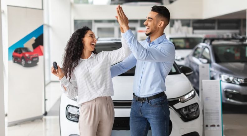 A woman is shown next to a car salesman after researching 'how to sell my car.'