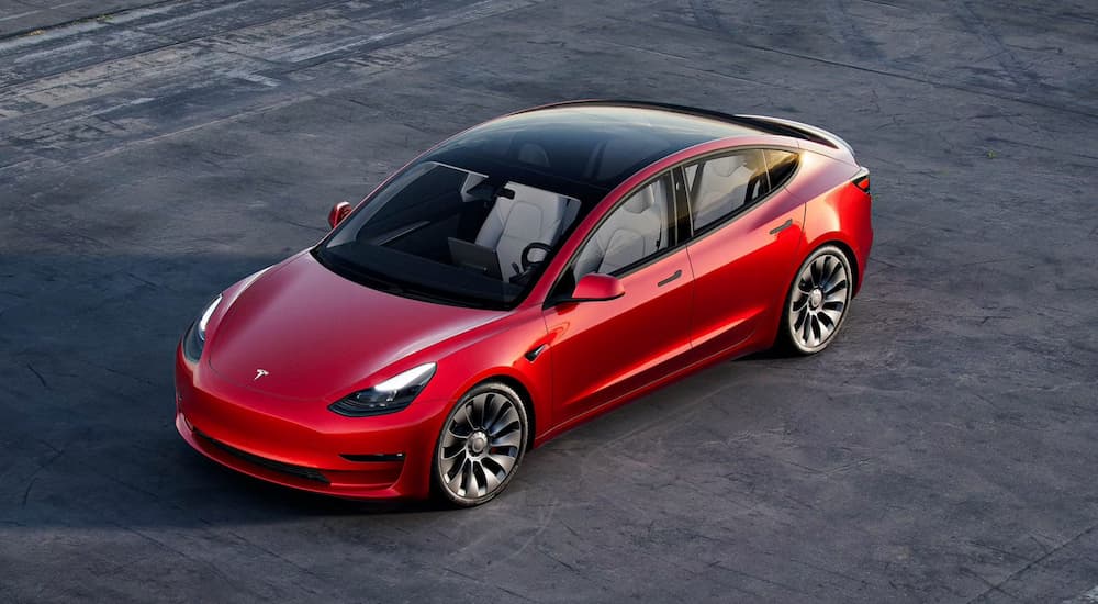 A red 2021 Tesla Model 3 is shown from a high angle.