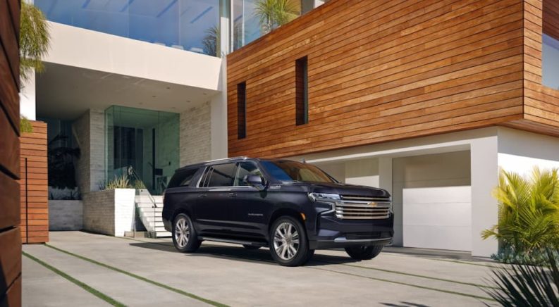 A black 2022 Chevy Suburban is shown parked outside of a modern home.