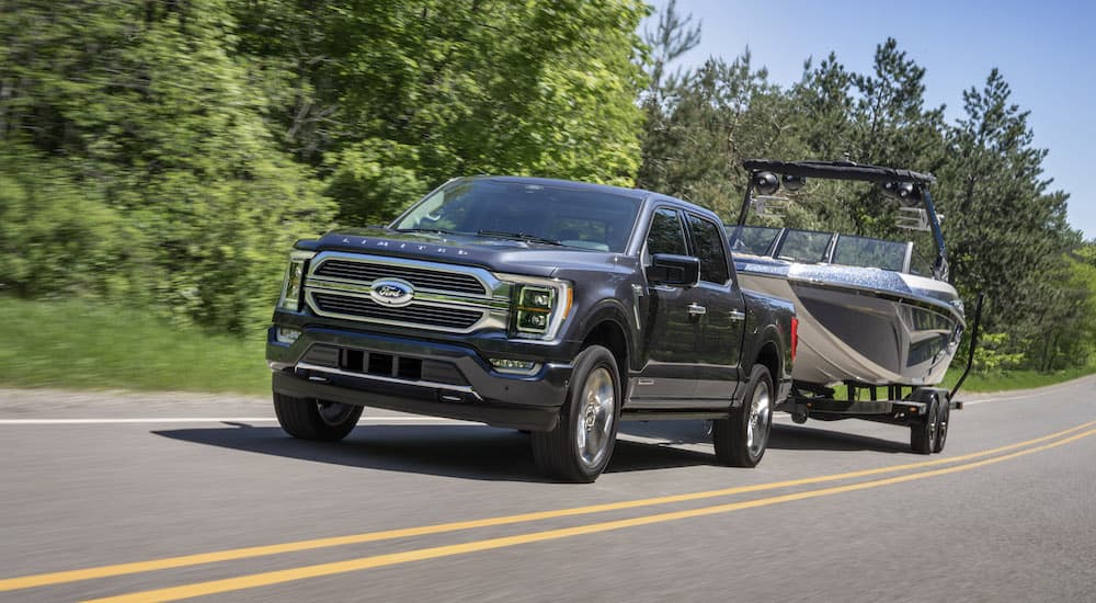 A black 2022 Ford F-150 Limited is shown from the front towing a boat on a trailer.