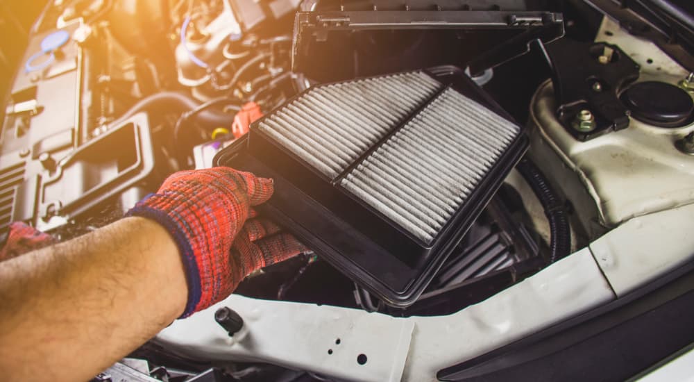 A mechanic is shown changing the air filter in a vehicle's engine.