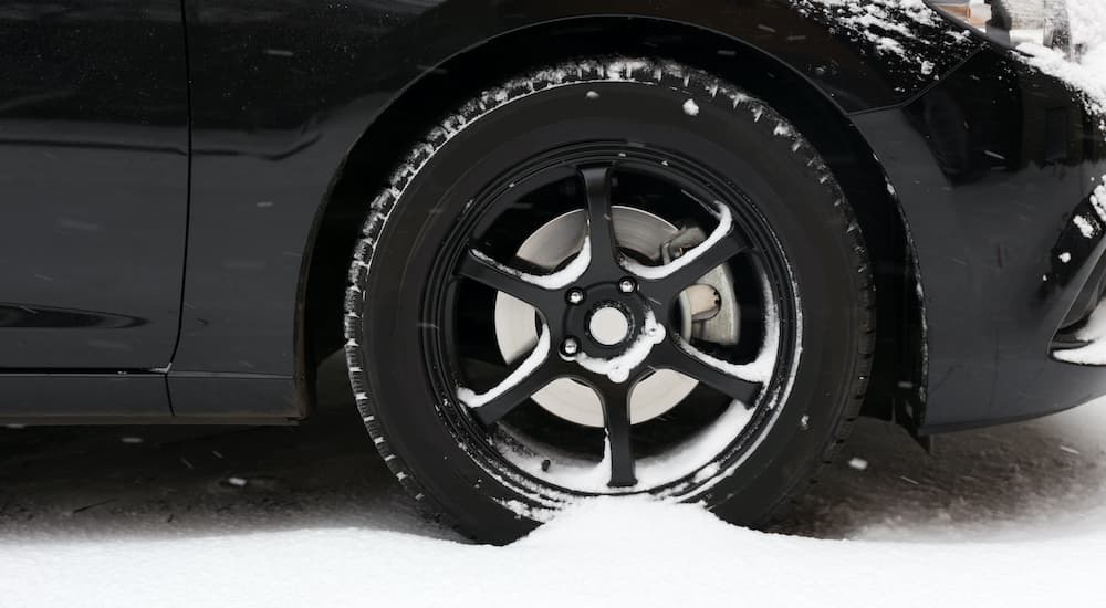 A close up shows black wheels in the snow after looking for snow tires for sale.