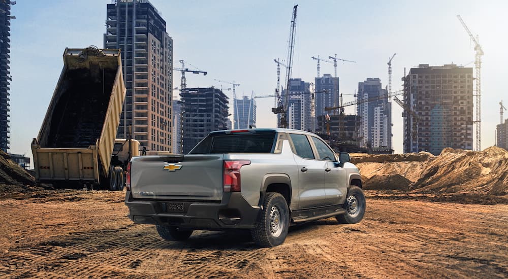 A silver 2024 Chevy Silverado EV is shown from the rear on a construction site.