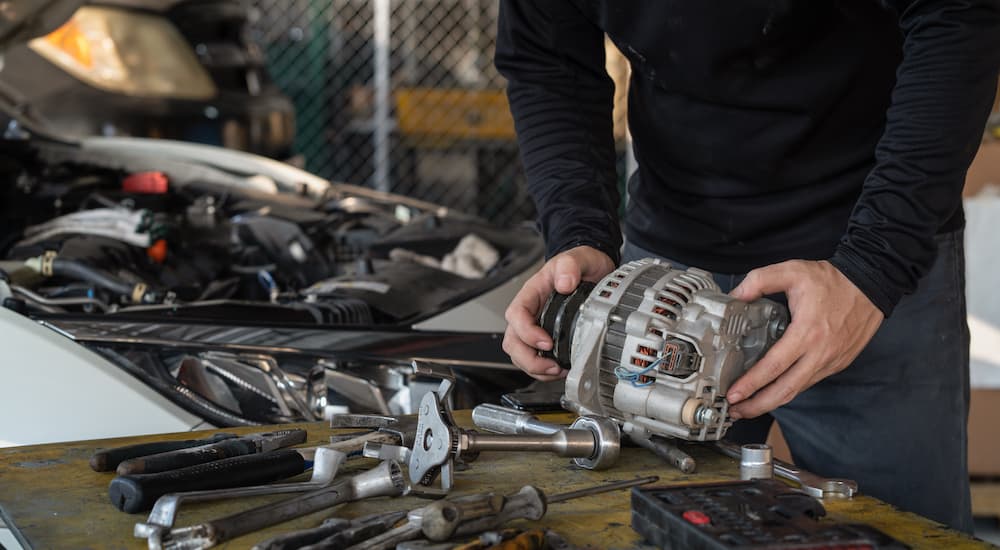A mechanic is shown working on an alternator that has been removed from a car.
