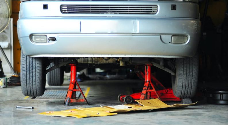 A silver car is shown on red jack-stands during an auto alignment near you.