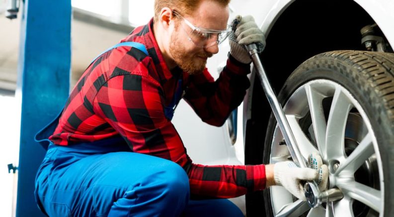 A person wearing safety goggles is shown torquing a lug nut during a DIY auto service near you.