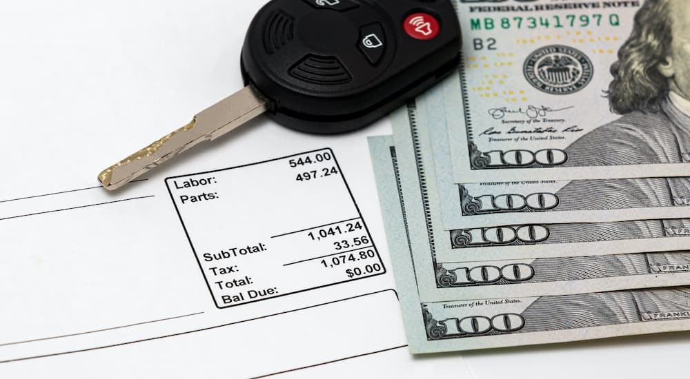 A close up shows cash, keys, and a repair receipt.