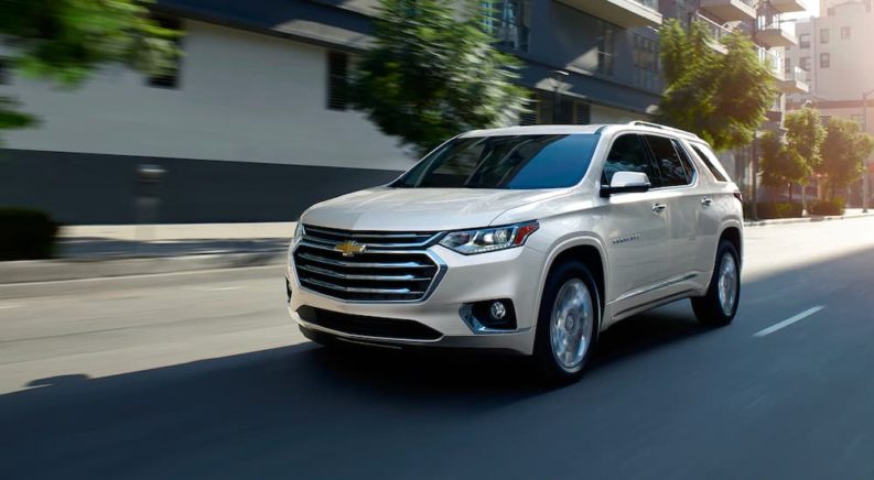 A white 2021 Chevy Traverse is shown driving on a city street.