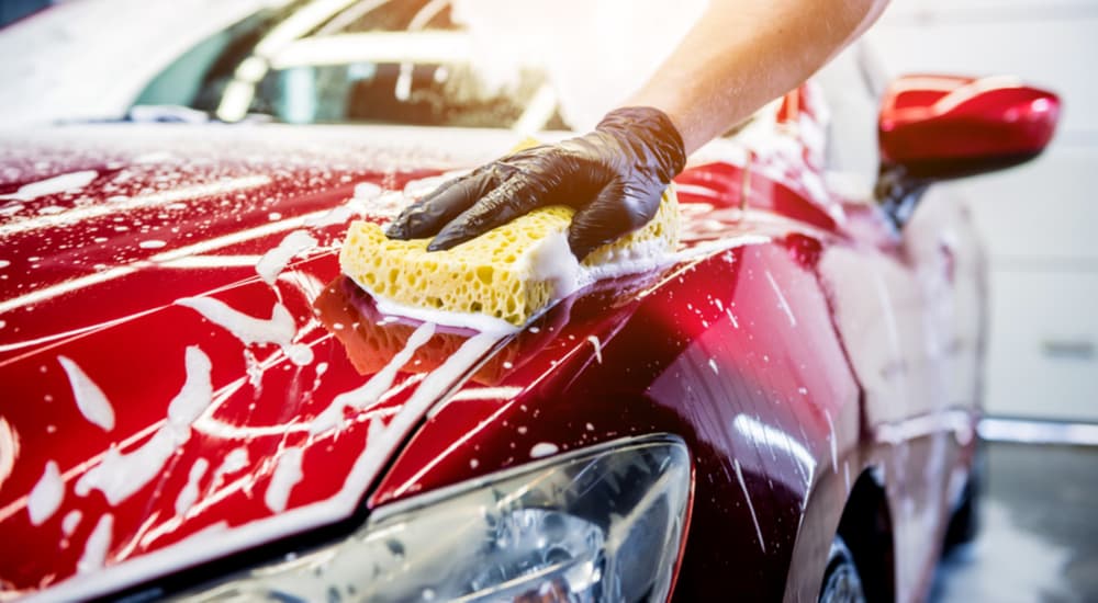 A person is shown washing their red vehicle after searching 'how to sell my car.'