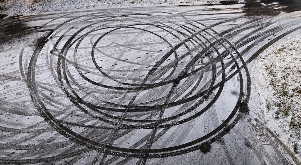 Multiple sets of tire tracks are shown in the snow from a high angle.