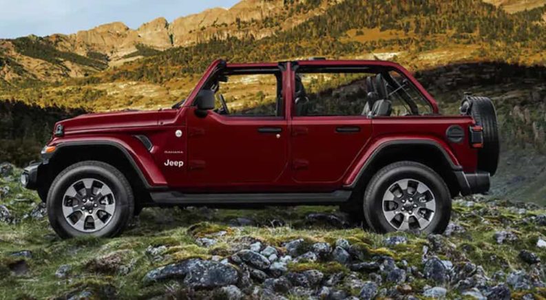 A maroon 2022 Jeep Wrangler Unlimited is shown from the side while parked in a rocky area after the owner searched 'auto alignments near me'.