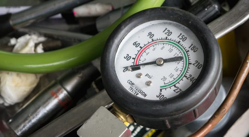 A close up shows the gauge on a compression tester.