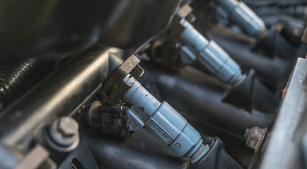 A close up shows light blue fuel injectors on a fuel rail.