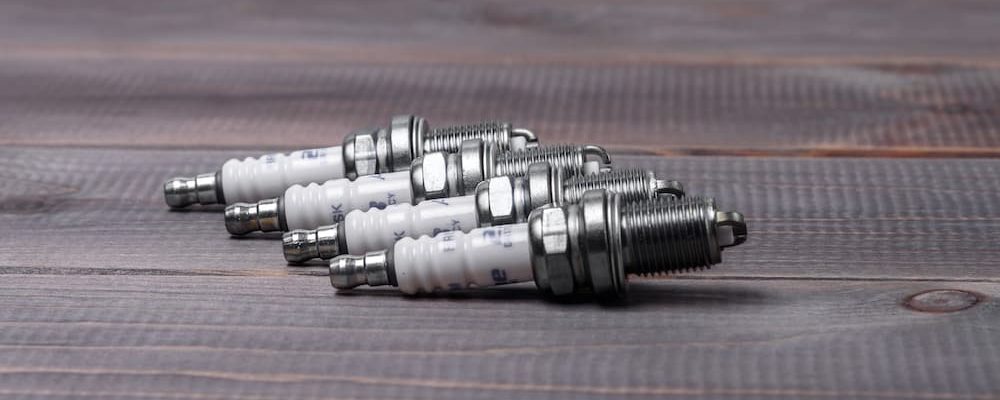 Four spark plugs are shown on a wooden table.