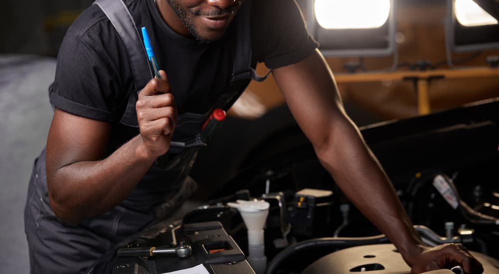 A man is shown working on a car engine.