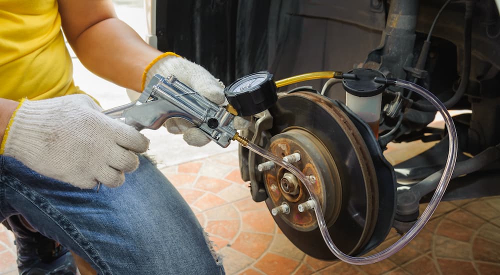 A person is shown inspecting the brake fluid during a car brake service.