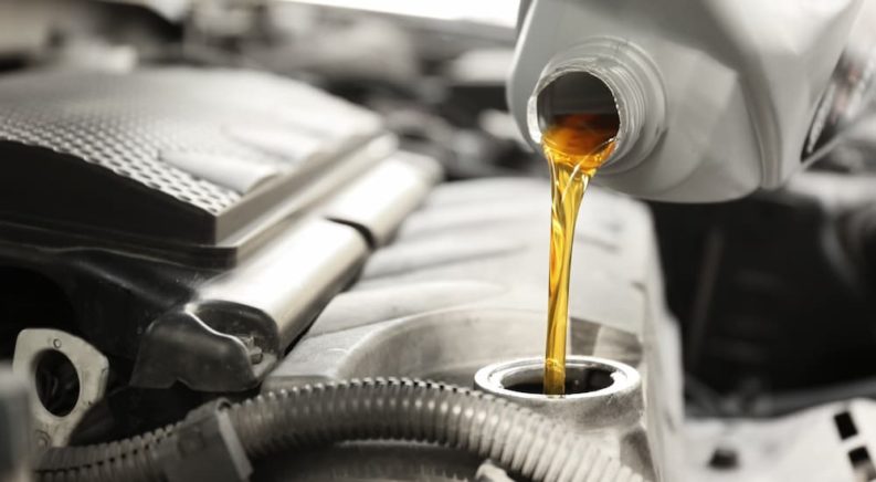 A close up shows oil being poured into a crankcase.
