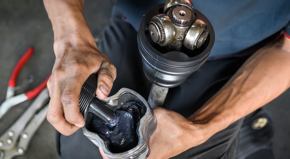 A mechanic is shown greasing a CV joint.