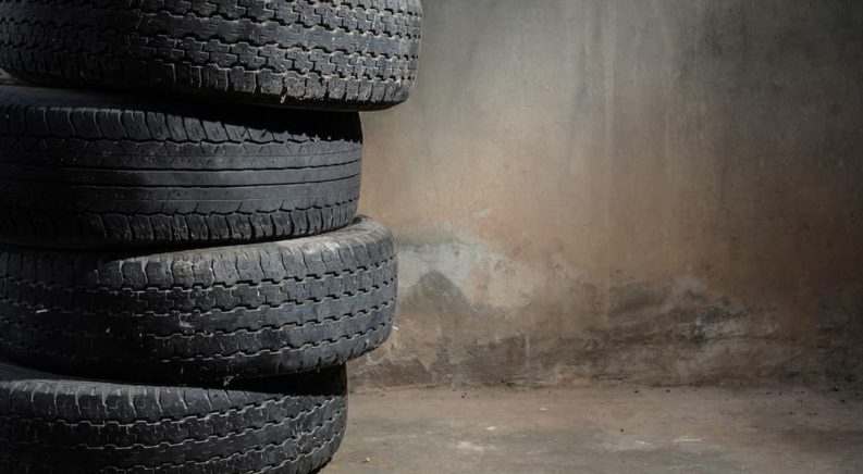 A stack of old tires are shown in an empty garage.
