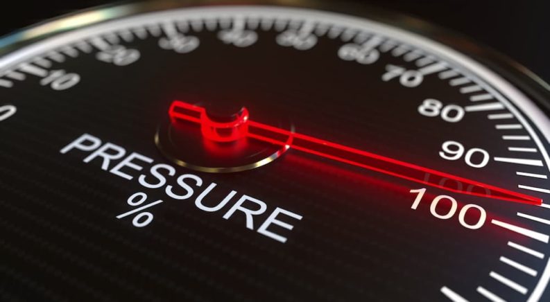 A red and black pressure gauge is shown during a leak down test.
