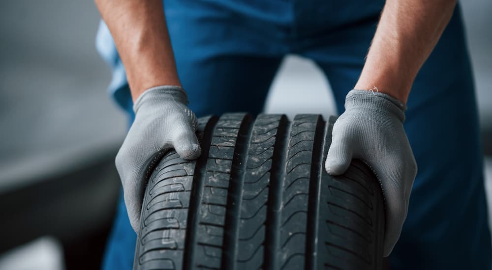A mechanic is shown holding a tire.