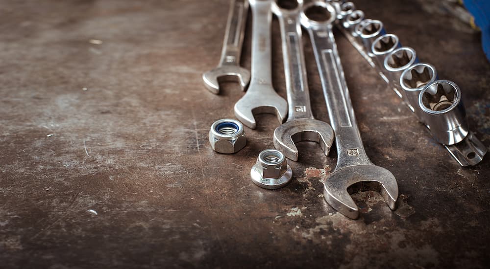 A set of wrenches and sockets are shown on a dirty shop table.