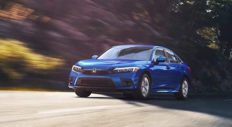 A blue 2022 Honda Civic is shown from the front while driving after getting a new set of Honda tires.