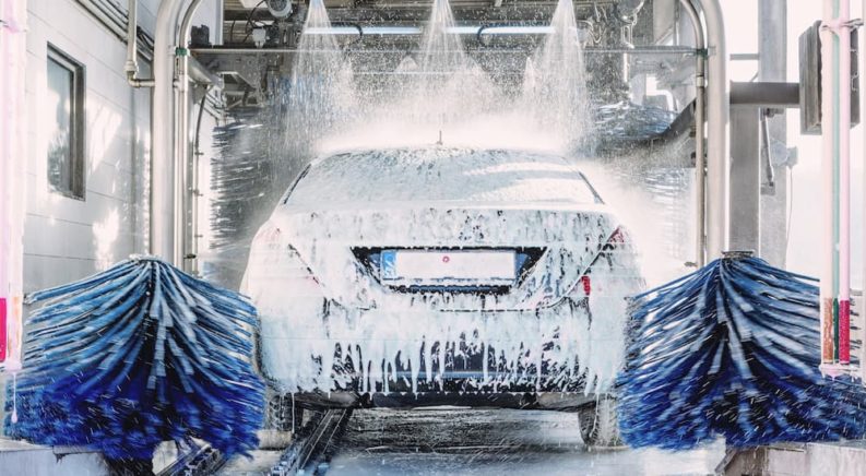 A vehicle is shown from the rear while going through an automatic car wash.