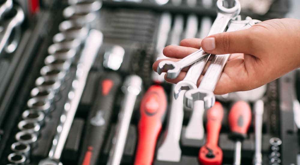 A person is shown holding wrenches over a tool box.
