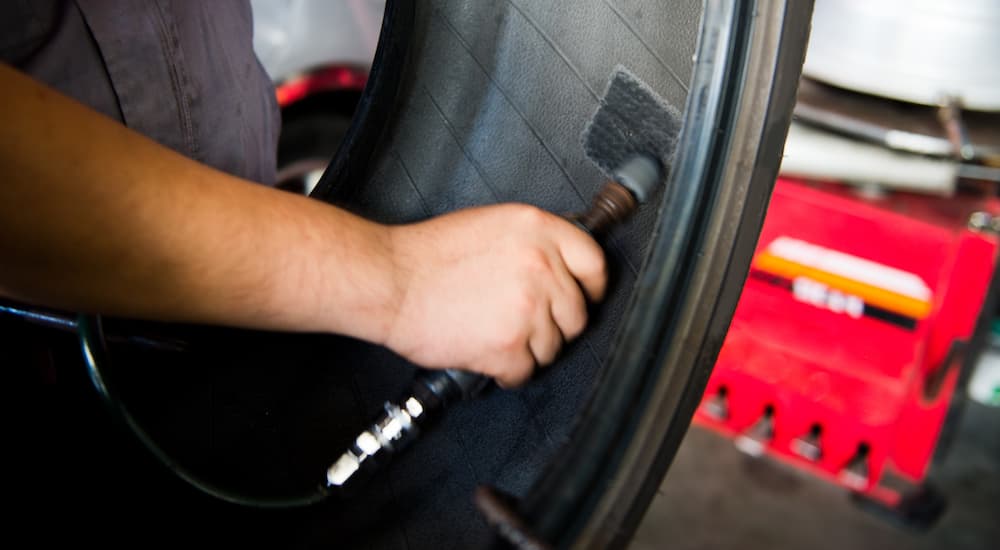 A close up shows a mechanic patching a tire at a trie repair shop.