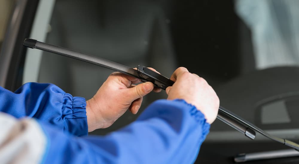 A mechanic is shown changing a windshield wiper blade.