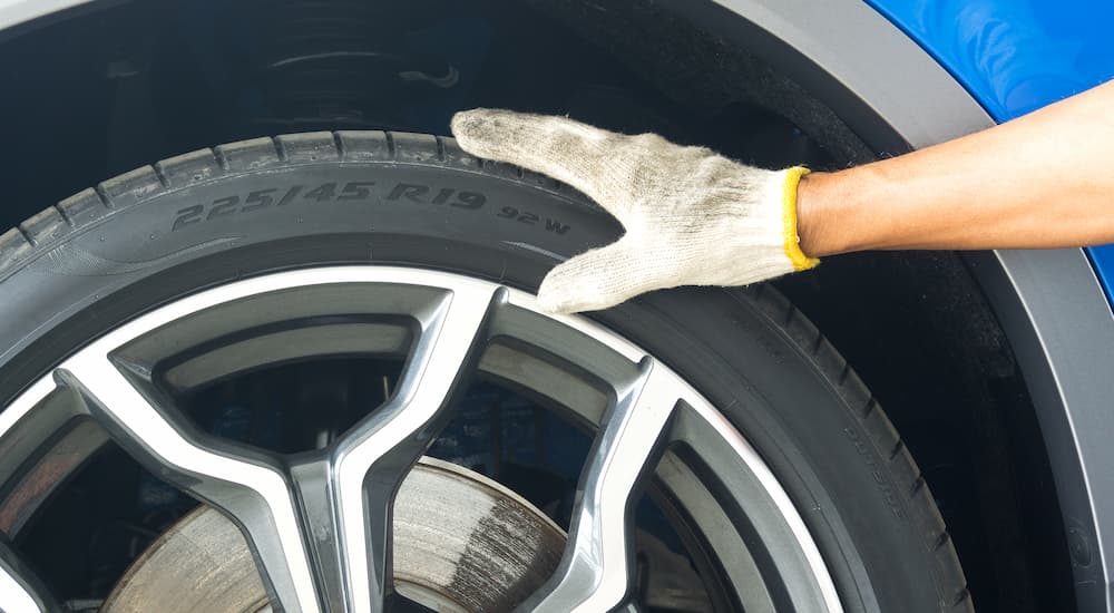 A mechanic is shown inspecting the side of a vehicle's tire.