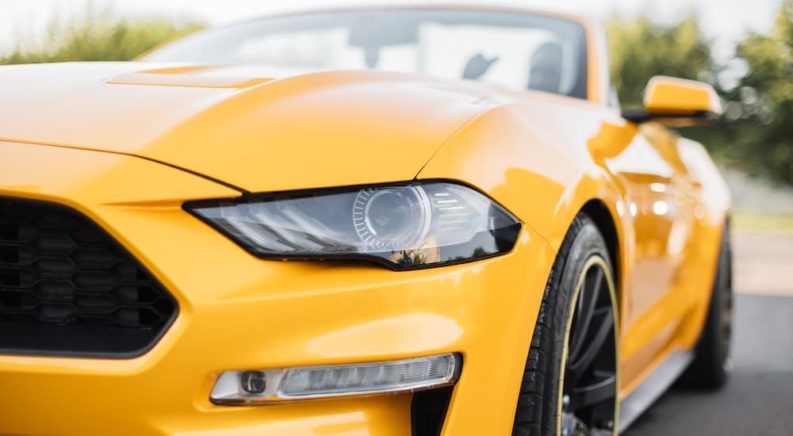 A close up shows the driver side headlight on a yellow 2019 Ford Mustang.