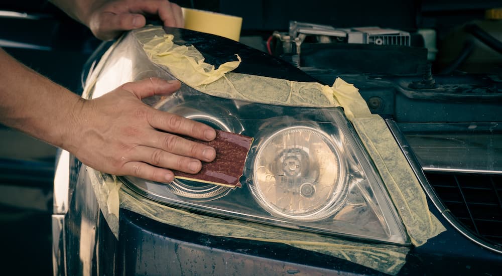 A close up shows a headlight being sanded during a headlight restoration.