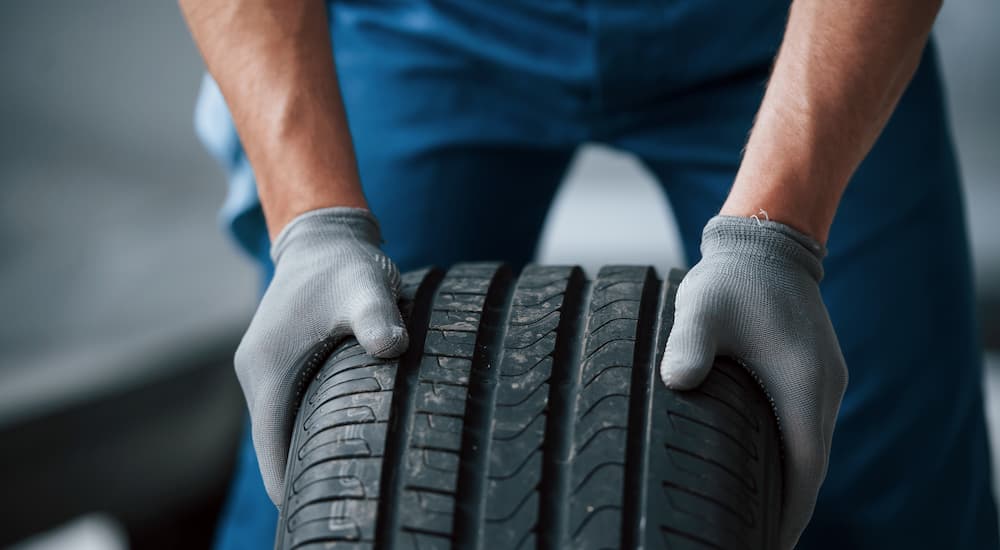 A mechanic is shown rolling a tire at a mechanics shop.