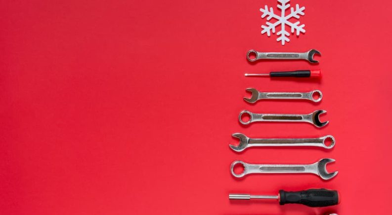 A set of tools are laid in the shape of a Christmas tree on a red background.
