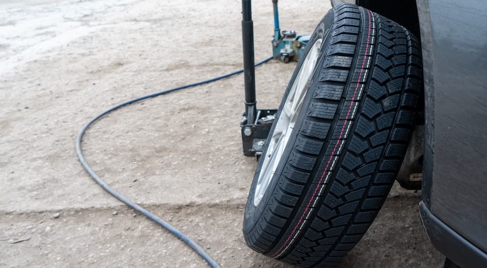 A tire is shown leaning against a vehicle.