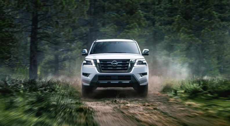 A white 2022 Nissan Armada is shown driving on a trail in the woods.