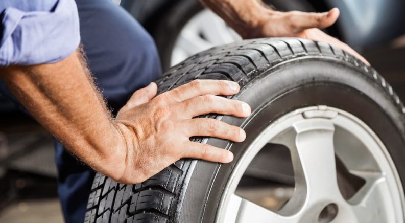 A person is shown checking the tread of a tire at a tire shop.