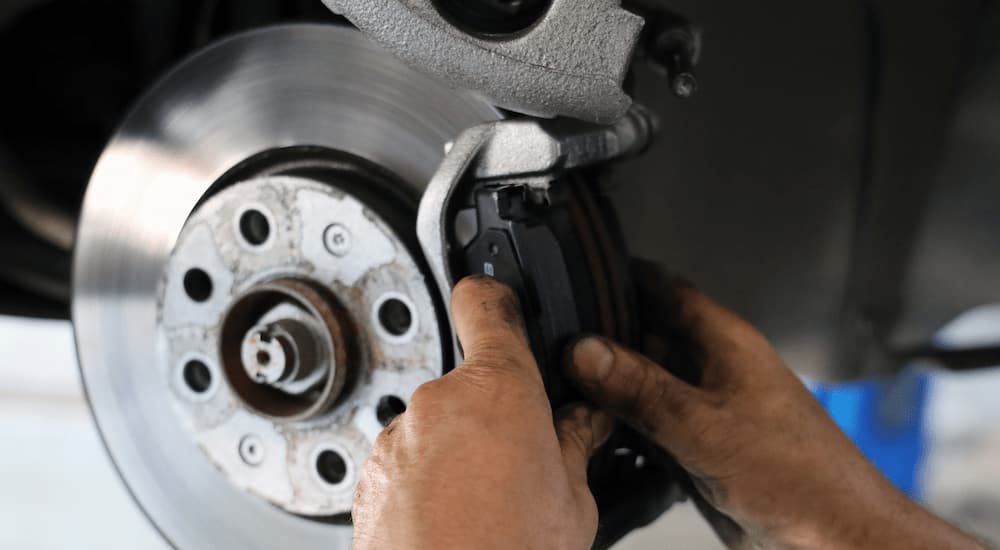 A close up of a mechanic inspecting brakes on a vehicle is shown.