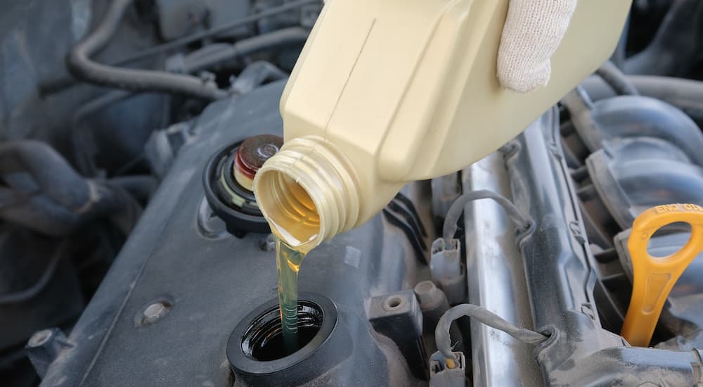 A hand is shown pouring oil into a used truck.