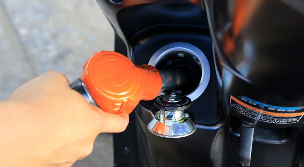 A person is shown filling the gas tank of a motorcycle.