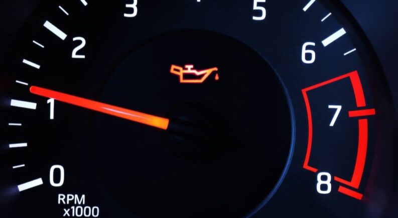 A check engine oil light is shown next to a tachometer.