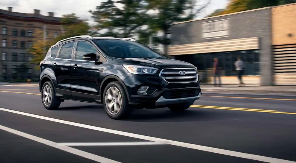 A black 2019 Ford Escape is shown driving on a city street after leaving a used Ford Escape.