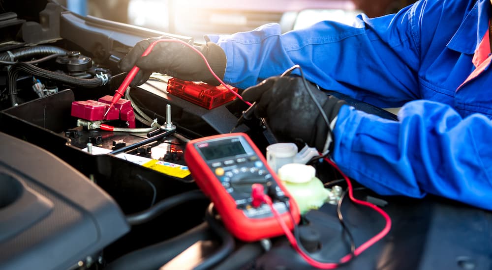 A mechanic is shown testing a battery with a multimeter.
