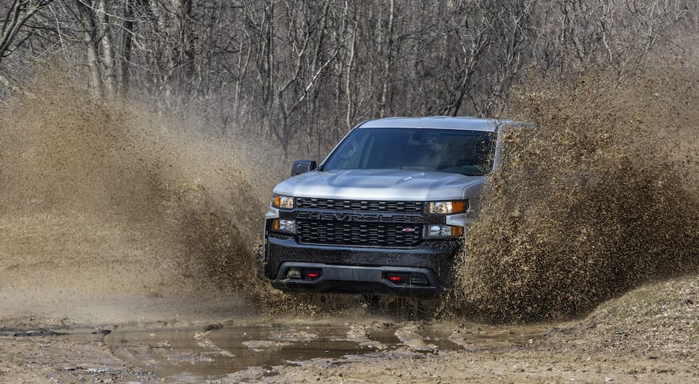 A grey 2020 Chevy Silverado 1500 Trail Boss is shown from the front while driving through mud.