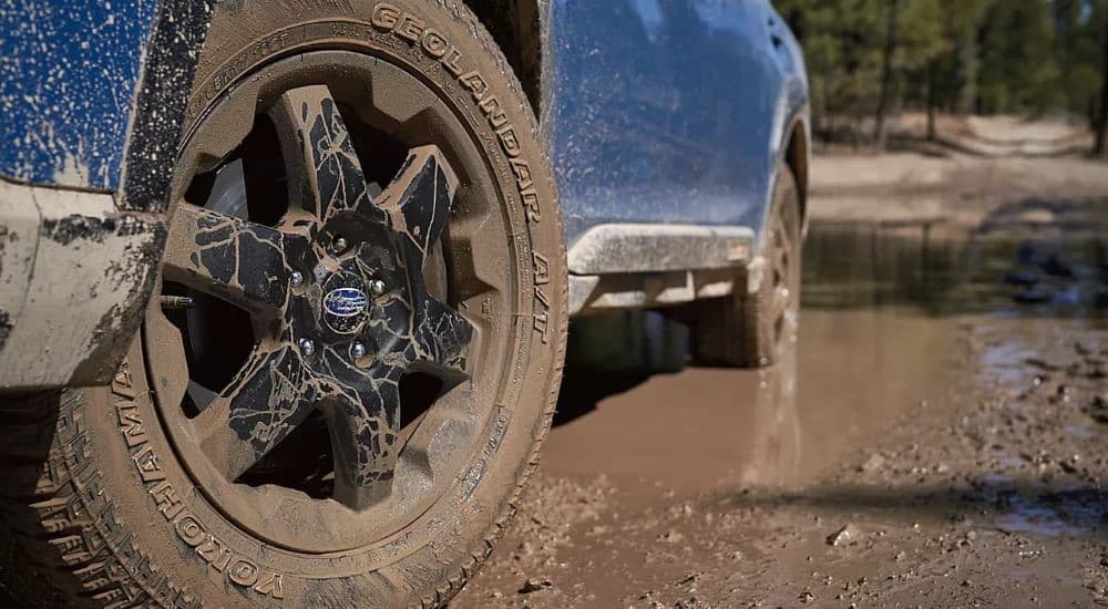 A muddy tire is shown on a bleu 2023 Subaru Outback Wilderness.