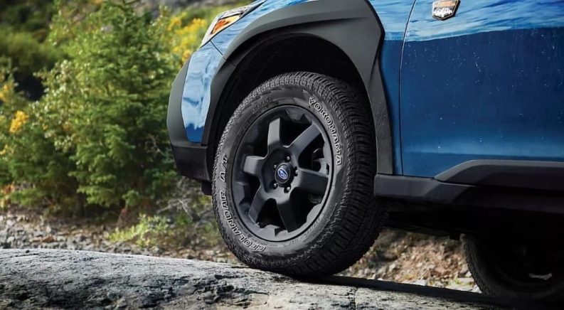 A close up shows the black rim and tire on a blue 2023 Subaru Outback Wilderness.