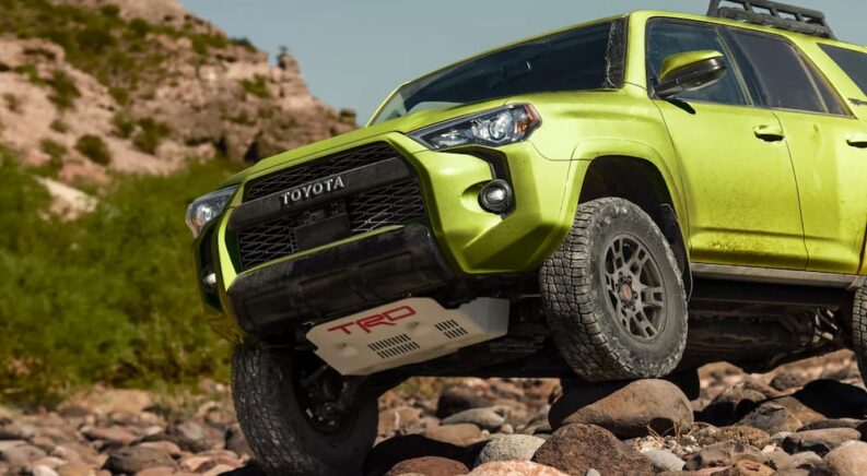 A green 2022 Toyota 4Runner TRD Pro is shown off-roading on a rocky trail after getting a Toyota service.